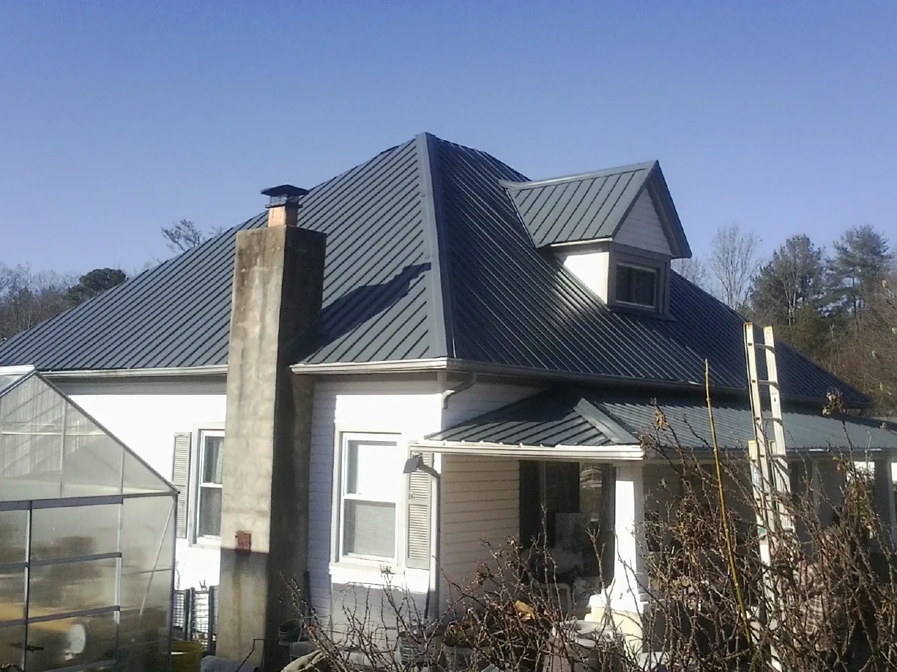 Dark blue standing seam metal roof on a white farmhouse with dormer — Slate & Tile Roof Repair by Roofing Brothers in Lowellville