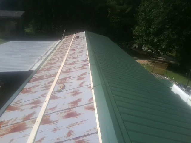 Old rusted panels beside newly installed green metal roofing — Wind Damage Roof Repair by Roofing Brothers in Lowellville