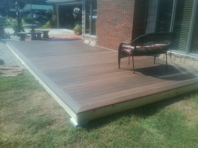 New wood deck and wicker chair beside a brick house in Lowellville