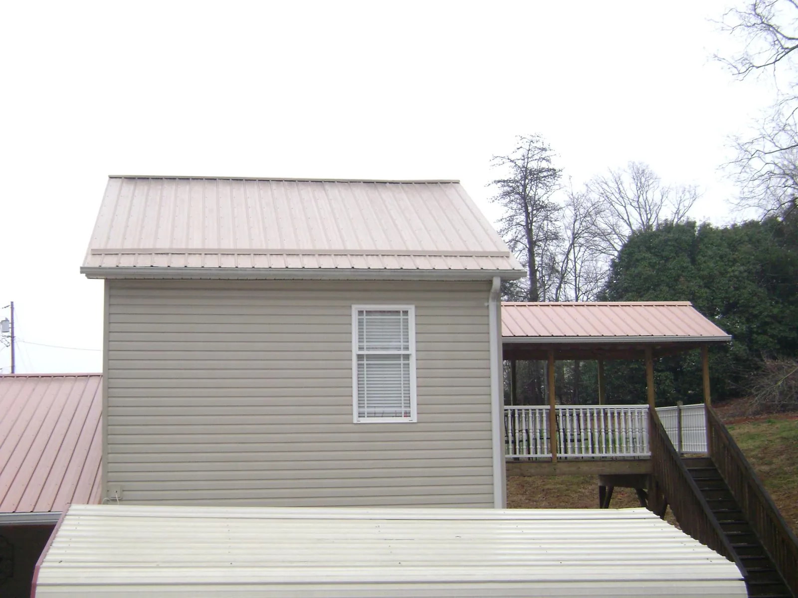 Tan metal roofs on a two story addition and attached porch, from a Roof Replacement job in Lowellville