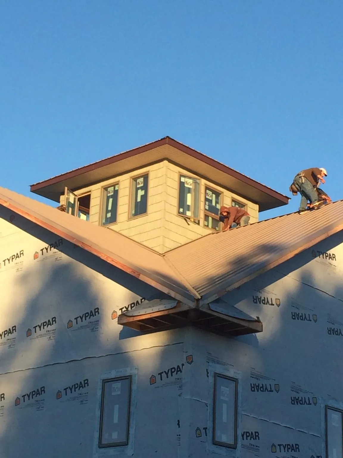 Roofers working around a rooftop cupola on a new metal roof at sunset — Roof Waterproofing in Lowellville by Roofing Brothers